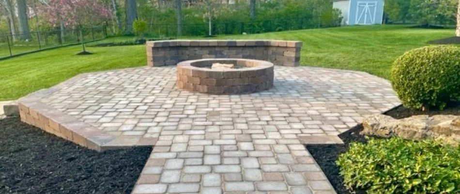 A fire pit on a patio in West Chester, OH, next to a seating wall. 