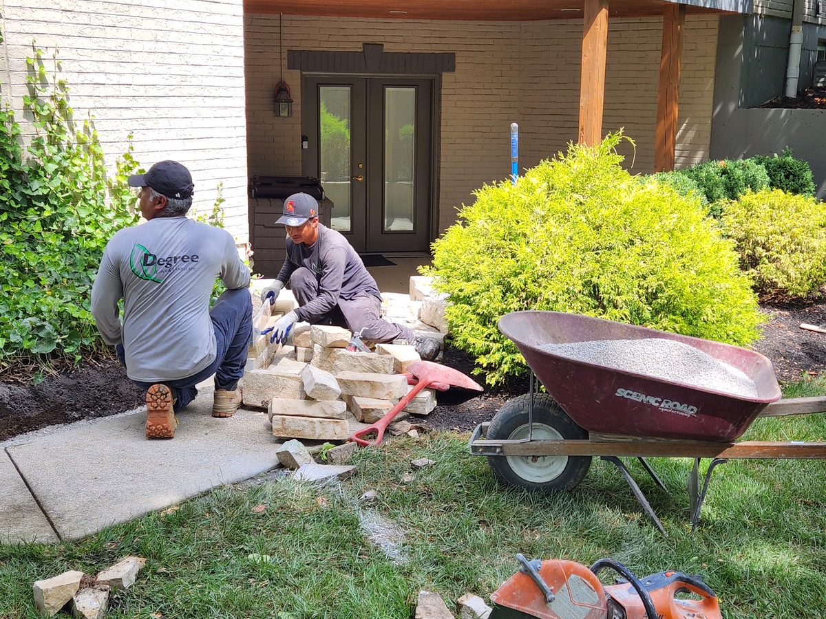 men installing a stone wall on a flower bed